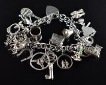 A silver charm bracelet with over twenty charms including a woman ironing by Nuno, radio, skier,
