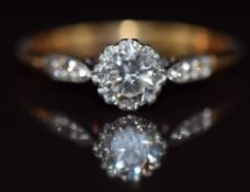 An 18ct gold ring set with a round cut diamond of approximately 0.85ct with further diamonds to
