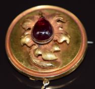 Victorian gold circular brooch set with a foiled garnet cabochon forming a grape upon an embossed