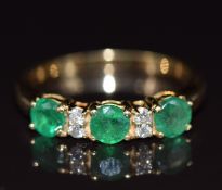 An 18ct gold ring set with three round cut emeralds, each approximately 0.35ct, and diamonds, 4.