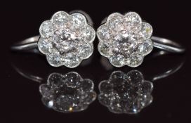 A pair of 9ct white gold earrings each set with nine diamonds in a cluster, the largest diamond
