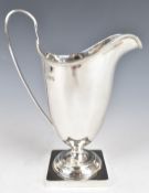 George V hallmarked silver jug of Georgian shape raised on a square base, Chester 1926, maker Stokes