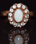 An 18k gold ring set with an opal cabochon surrounded by spinel, 4.4g, size T