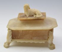 Carved alabaster octagonal covered casket with lamb surmount, raised on lion paw feet, probably