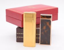 Two vintage lighters comprising Cartier gold plated example with reeded decoration, serial number