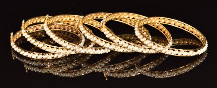 Six 22ct gold bangles set with natural pearls, in original box 'Mudaifa Jewellery Bahrain', 64.2g
