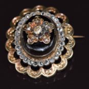 Early Victorian brooch set with a jet cabochon mounted with rose cut diamonds in a floral setting