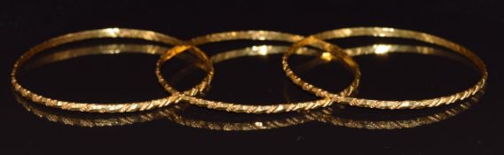 Three 21k gold bangles with faceted decoration, 31.6g