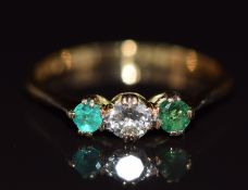 An 18k gold ring set with an old cut diamond of approximately 0.2ct and two emeralds, 1.8g, size N