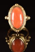 A 14k gold ring set with a coral cabochon, with rope twist and sphere decoration, 10.5 g, size O
