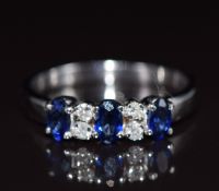An 18k white gold ring set with three oval cut sapphires and four diamonds, 3.5g, size N