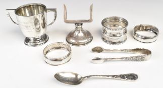 Hallmarked silver items comprising twin handled trophy cup, height 5.5cm, three various napkin