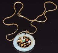 A 14k gold pendant set with a jade disc with a gold foliate design to the centre set with jade