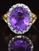An 18ct gold ring set with an oval cut amethyst of approximately 4.1ct surrounded by diamonds, 6.4g,