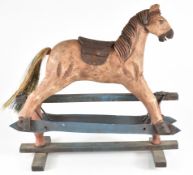 Carved wooden model of a rocking horse with leather saddle and straw tail, 36cm long.