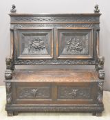 Carved oak settle with lions forming the arms, length 122cm