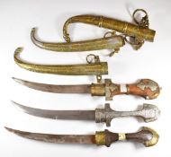 Three Moroccan Jambiya daggers, all with ornately engraved silver and brass scabbards and curved