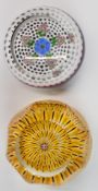 Two Perthshire glass paperweights, one with central blue and yellow flower surrounded by pink and