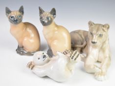 Four Copenhagen animal figures comprising recumbent lioness, Polar Bear cub and two Siamese cats,