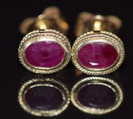 A pair of 9ct gold earrings set with an oval cut ruby to each, 0.8g