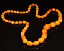 A 1920's Baltic amber necklace made up of 57 butterscotch / egg yolk coloured oval beads, 44.9g