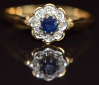 An 18ct gold ring set with a sapphire surrounded by diamonds in a cluster, 3g, size O