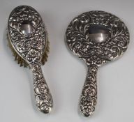 Hallmarked silver hand mirror and brush decorated with embossed faces in foliage, marks indistinct