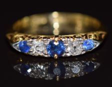 A c1915 18ct gold ring set with diamonds and sapphires in a scrolling setting, 3.4g, size L