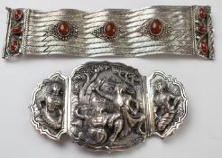 A white metal belt buckle with relief decoration depicting a Thai scene and a white metal bracelet