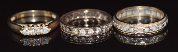 Two 9ct gold eternity rings and a 9ct gold ring set with three diamonds, 7.5g, size O, K & N