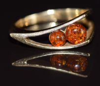 A 9k gold ring set with two pressed amber cabochons, 3.9g, size O