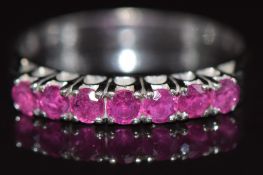 A 14k white gold ring set with seven round cut rubies, 2.9g, size O