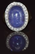 A 9ct gold ring set with a tanzanite cabochon surrounded by diamonds, 6.9g, size M