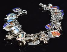 A silver charm bracelet with 25 silver charms including enamel shields, bus, etc