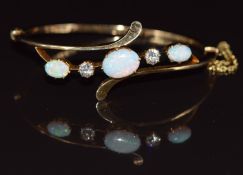 A c1900 18ct gold bangle set with three oval opal cabochons and two old cut diamonds, each