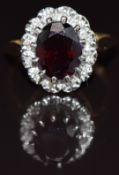 An 18ct gold ring set with an oval cut almandine garnet surrounded by diamonds, 4.9g, size P