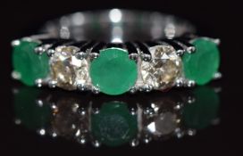 An 18ct white gold ring set with two diamonds each approximately 0.38ct, and three emeralds each