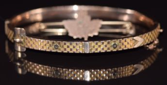 A 9ct gold buckle bangle with textured decoration (5.8g) and a maple leaf brooch