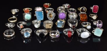 Thirty three silver rings set with quartz, ruby, pressed amber, etc
