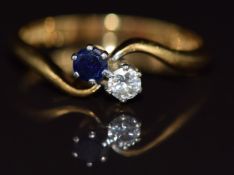 An 18ct gold ring set with a diamond and sapphire in a twist setting, 2.7g, size M