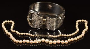 A silver buckle bangle / cuff with engraved decoration, c1900, and a cultured pearl necklace