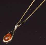 A 9ct gold pendant set with a pressed amber cabochon and a 9ct gold chain, 3g