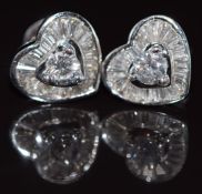 A pair of 18k white gold earrings in the form of a heart set with round and baguette cut diamonds,