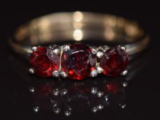 A 9ct gold ring set with three round cut garnets, 2.5g, size S