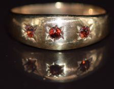 A 9ct gold ring set with three garnets in star settings, 1.8g, size I