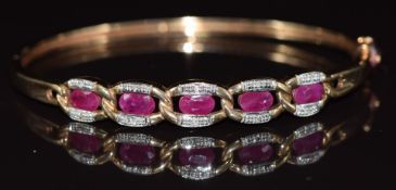 A 9ct gold bangle set with five oval cut rubies and diamonds, 11.9g