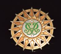 A 9ct gold brooch set with green enamel initials and diamonds inside a sunburst design, by Garrard &