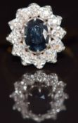 An 18ct gold ring set with an oval cut sapphire surrounded by diamonds, 4.8g, size P