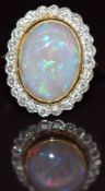 An 18ct gold ring set with an opal cabochon surrounded by diamonds, 6.3g, size M
