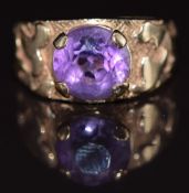 A 9ct gold ring set with a round cut amethyst, with textured shoulders, 4.2g, size E